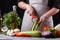 Young woman in gray apron peeling cucumber