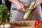 Young woman in gray apron peeling cucumber