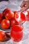 Young woman in a gray apron pours juice blood orange