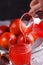 Young woman in a gray apron pours juice blood orange