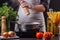 Young woman in a gray apron seasoning mushroom sauce