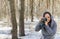 Young woman in gray coat photographing on old photo camera in forest. Pretty female taking photos with old camera in