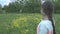 A young woman in gray waving to her friends through a flower field. The girl waves to a group of friends of tourists.