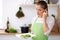 Young woman in green apron is cooking in a kitchen. Housewife is offering fresh salad.