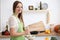 Young woman in the green apron cooking in the kitchen. Housewife slicing fresh salad.