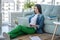 Young woman in green pants sitting on the floor and chatting in internet