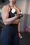 Young woman in gym working out biceps by dumbbell closeup