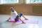 Young woman gymnast sitting on the yoga mat and bending back