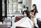 Young woman and hairdresser wearing protective masks at salon, free spac