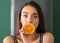 Young woman with half of orange in kitchen