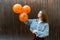 Young woman with halloween inflatable orange ballons on brown background, party concept