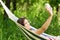 Young woman in a hammock in garden doing snapshot.