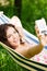 Young woman in a hammock in garden doing snapshot.