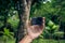 Young woman hand holding extreme action camera in the asian green park. Tropical Bali island, Indonesia.