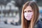 Young woman with hand made face nose mouth mask portrait, blurred empty city square behind her. Can be used during coronavirus