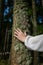 Young woman hand palms tree trunk with mug and moss in the forest