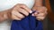 Young woman hands knitting a blue scarf