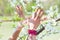 Young woman hands with lot of rings and bracelets in bird symbol gesture in front cherry blossom closeup