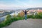Young woman with hands up on the hill over Vltava river and brid