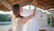 Young woman hanging laundry at windy terrace closeup. White linen air drying