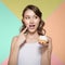 Young woman happily eating a sweet dessert. To bring a finger in a sweet cream to a mouth. Colorful bright background