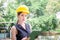 Young woman in hardhat holding clipboard checklist and looking at camera, Quality control concept