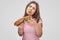 Young woman has piece of green lettuce in mouth. She holds tasty burger. Model enjoy. Isolated on grey background.