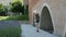 Young woman in a hat with a backpack walks along the ancient walls and touches her hand. Travel and architecture