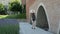 Young woman in a hat with a backpack walks along the ancient walls and touches her hand. Travel and architecture. Back view