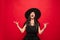 Young woman in hat and dress as a witch on red background