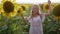 Young woman in a hat flirts and smiles near sunflowers. Portrait view.