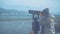 A young woman in a hat looks at the sea and mountains in a binocular, atmospheric video. In the background flocks of