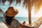 Young woman in hat relaxing in hammock on the beach. Vacation concept, rear view of a woman relaxing and enjoying the sun on