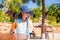 Young woman in hat sitting in tropical cafe near