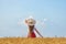 Young woman in hat stands in wheat field on blue sky background. Weekend outdoors