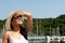 Young woman with hat summer dress and sunglasses walks pier of m