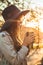 Young woman in a hat with thermos thermo cup outdoor portrait in soft sunny daylight. Autumn. Sunset. Cozy