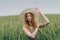 Young woman in a hat walking in a wheat field, enjoys life and summer. Wheat field.Healthy lifestyle Concept