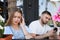 Young woman having boring date with guy in outdoor cafe