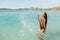 Young woman having fun and splashing water on beach. Leisure and relaxation