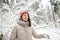 Young woman having fun on a walk in snow covered pine forest on chilly winter day. Female hiker exploring nature