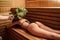 young woman having a russian sauna procedure with bath brooms from oak leaves