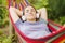 Young woman in headphones listening to music while resting in hammock outdoors