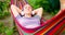 Young woman in headphones listening to music while resting in hammock outdoors