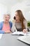 Young woman helping an old senior woman doing paperwork and administrative procedures with laptop computer at home