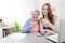 Young woman helping an old senior woman doing paperwork and administrative procedures with laptop computer at home