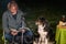 Young woman and her Australian Shepherd outside by a campfire. Reading a book at dusk. Bread, cheese and wine on the