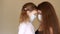 Young woman and her baby girl medical mask. Mother and daughter huging and looking at each other. Isolated on background
