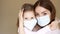 Young woman and her baby girl medical mask. Mother and daughter huging and looking at each other. Isolated on background