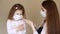 Young woman and her baby girl in medical mask using liquid hand sanitizer during quarantine. Mother and daughter using